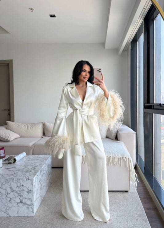 Tailleur Federica composto da blazer con cintura in vita e pantaloni palazzo dalla linea fluida. Le maniche impreziosite da morbide piume aggiungono un tocco glamour e sofisticato. Perfetto per eventi, serate eleganti e occasioni speciali.