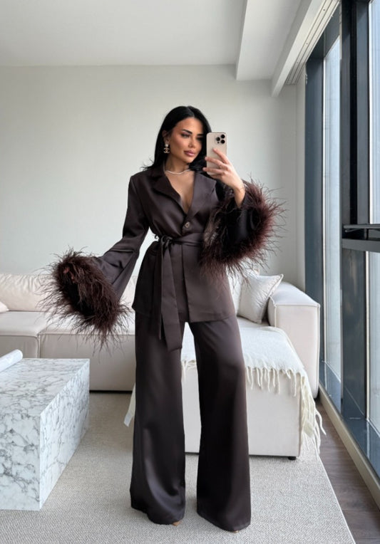 Tailleur Federica composto da blazer con cintura in vita e pantaloni palazzo dalla linea fluida. Le maniche impreziosite da morbide piume aggiungono un tocco glamour e sofisticato. Perfetto per eventi, serate eleganti e occasioni speciali.