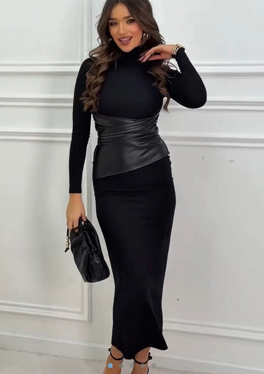 Abito lungo nero dal design raffinato, realizzato in tessuto invernale elasticizzato che valorizza la silhouette. Il collo alto e le maniche lunghe donano eleganza e comfort, mentre la fascia in vita effetto pelle crea un contrasto moderno e femminile.